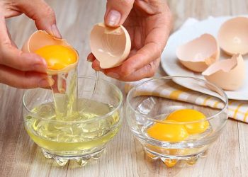 Wanita memisahkan kuning dan putih telur