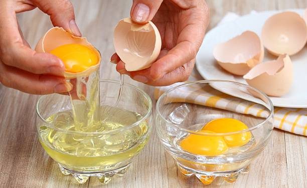 Wanita memisahkan kuning dan putih telur